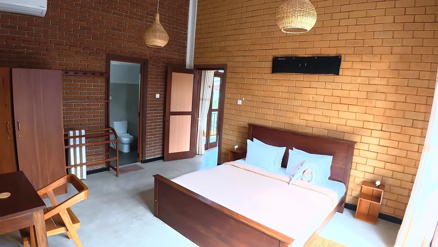 Chambre aux murs de briques et lit en bois — Syndeo Garden, Hikkaduwa