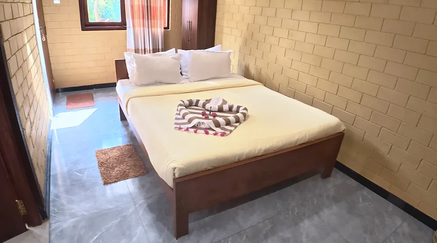 Chambre aux briques jaunes et lit en bois — Syndeo Garden, Hikkaduwa