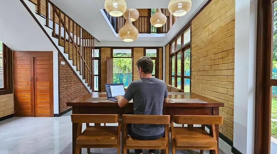 Un voyageur travaille sur son ordinateur portable à la table de la villa — Syndeo Garden, Hikkaduwa